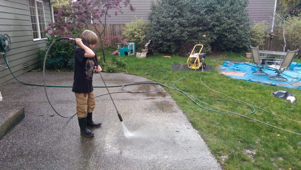 kid pressure washing a patio
